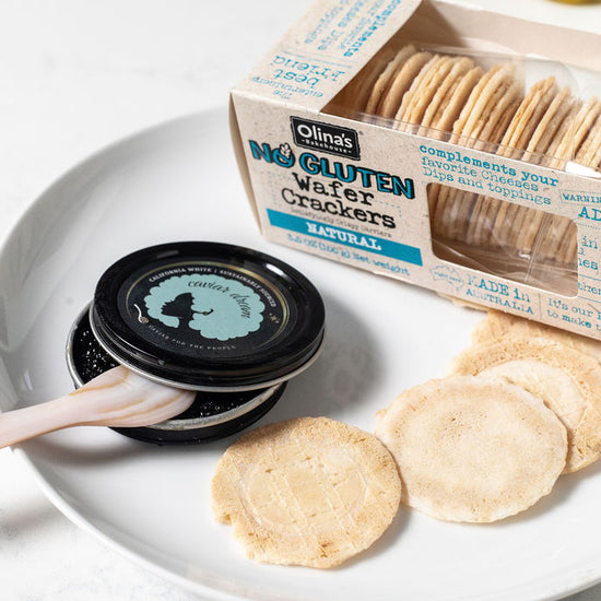 Olina's gluten-free wafer crackers on a plate with a container of California White caviar.