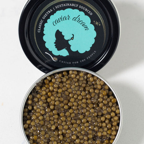 Open tin of caviar with visible Caviar Dream brand logo on a white background