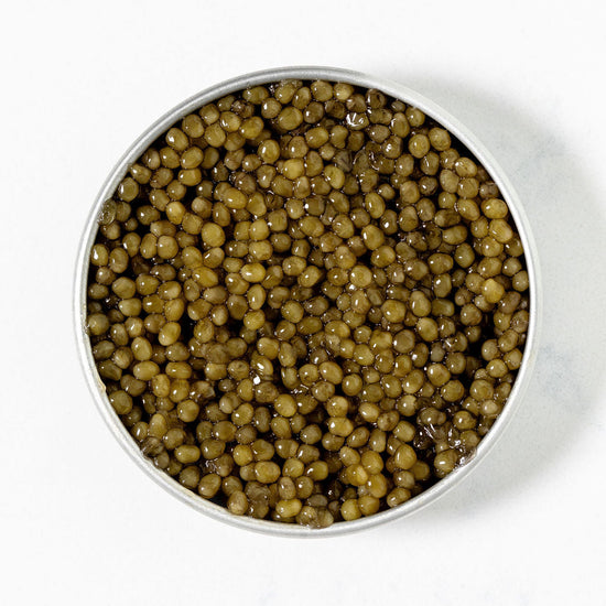 Close-up of Imperial Osetra -- golden-olive green caviar on a white background