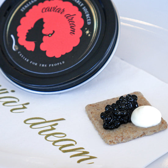 Caviar Dream container with caviar and a dollop of creme fraiche on a cracker.