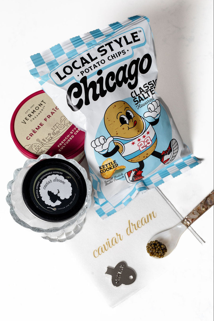 Packaged potato chips with a decorative napkin and Kaluga Hybrid caviar on a white background