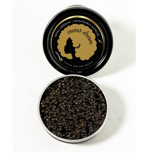 Open container of Royal Siberian caviar with 'Caviar Dream' branding on a white background. Dark brown to light black roe.
